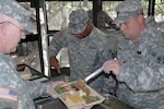 Army Staff Sgt. Joey K. Falls (left) and Spc. Seth Grove (right) of the Virginia National Guard's 1032nd Transportation Company serve 1st Sgt. Ernest T. Miller out of a mobile kitchen trailer. The mobile kitchen trailer was set up as a requirement of the Connelly Competition for which they were competing.