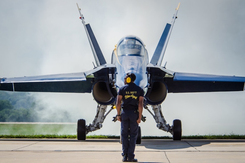 An airman stands in front of a jet.
