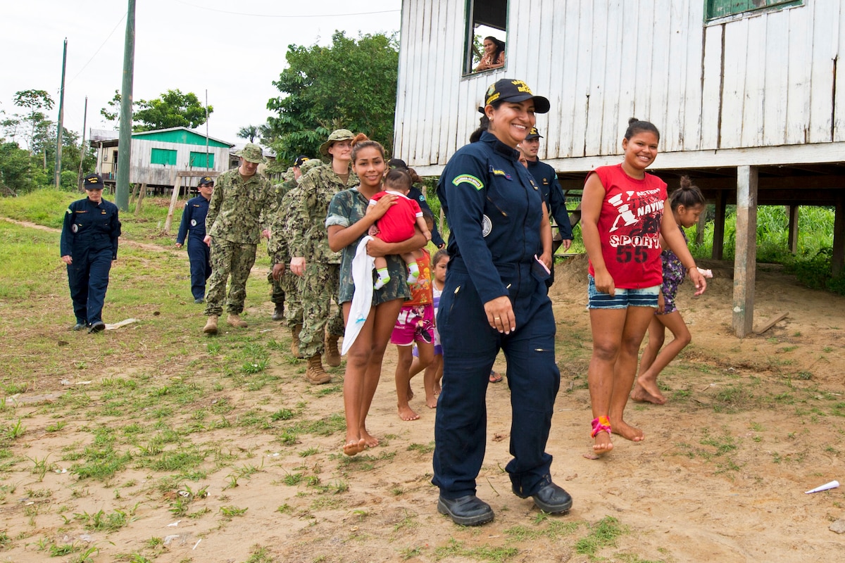 A team of U.S. and Brazilian navy doctors walk with residents in a Brazilian village.