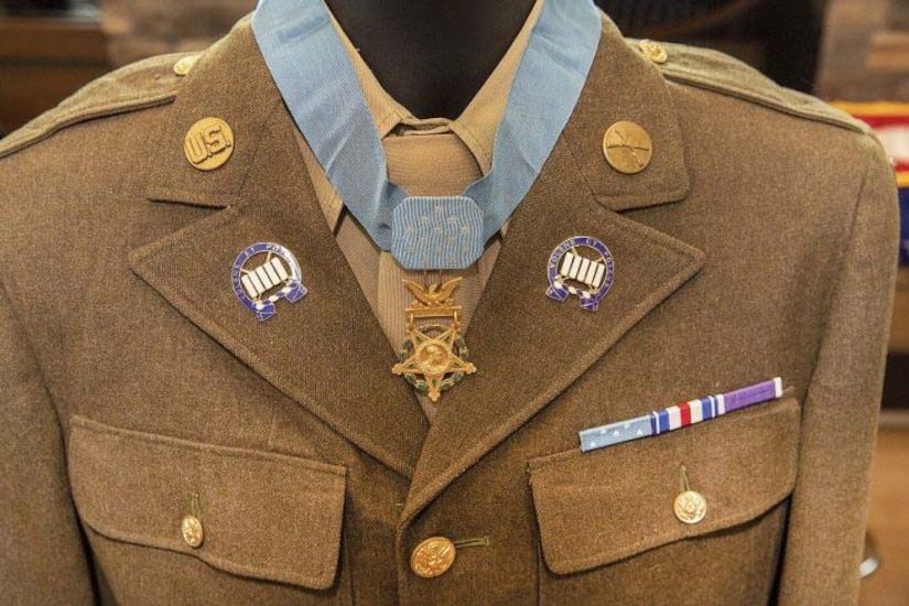 A mannequin holding a World War II-era Army dress uniform is decorated with a Medal of Honor.