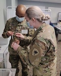 U.S. Army 2nd Lt. Brianna Russell, right, a medical team reconnaissance liaison, and U.S. Army Spc. Bryan Coker, a medic serving with the Michigan National Guard’s (MING) COVID-19 Task Force Spartan, prepare a COVID-19 vaccination at Spectrum Health Butterworth Hospital Grand Rapids, Michigan, Dec. 16, 2020. The MING and the Michigan Department of Health and Human Services have been working together throughout the pandemic.