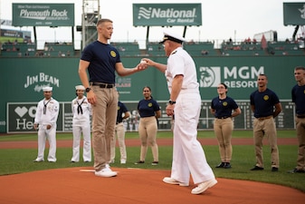 Chief of Naval Operations Adm. Mike Gilday hands the first pitch to a newly-enlisted Navy Sailor to throw at a Red Sox baseball game at Fenway Park, Boston.