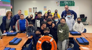 BM3 Corey Connolly (left) and BM2 Daniel Noel, Marine Safety Security Team (MSST) Houston Partnership in Education (PIE) volunteers, pose with students from Carter Lomax Elementary School in Pasadena, Texas during a Coast Guard career day
