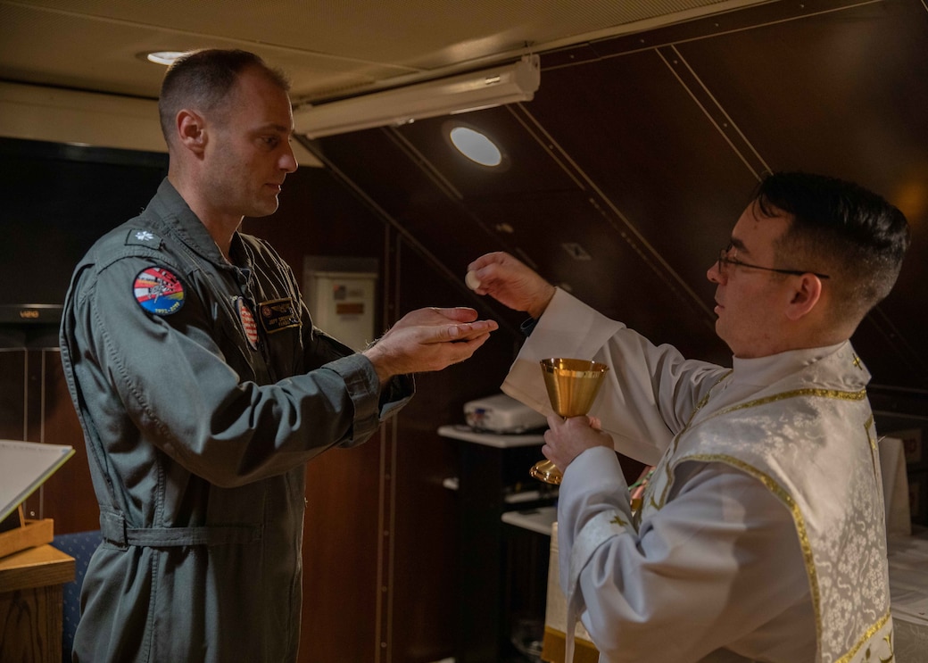 Lt. Brad Guillory, a chaplain, assigned to the Nimitz-class aircraft carrier USS George H.W. Bush (CVN 77), gives Communion to Cmdr. Jeff Drewiske, assigned to Carrier Strike Group (CSG) 10, during All Saint’s Day Catholic mass in the ship’s chapel, Nov. 1, 2022.