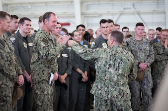 Chief of Naval Personnel Vice Adm. Rick Cheeseman holds mic out for a VP-9 Sailor during an all-hands call inside a hangar bay