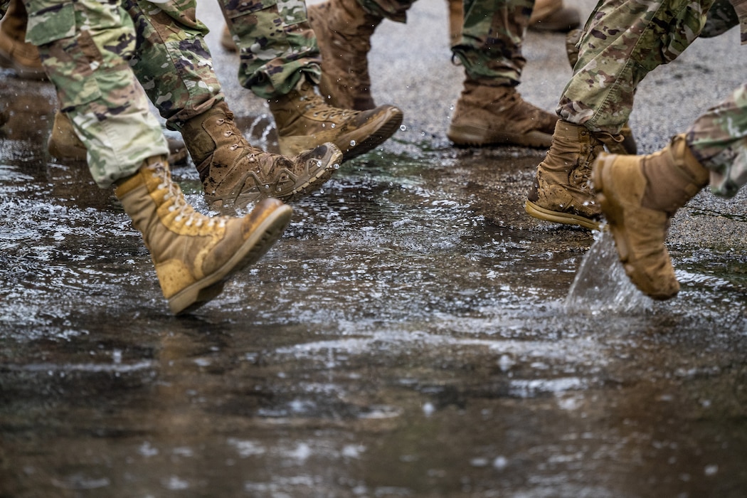 Close-up of military boots marching through a puddle in the rain