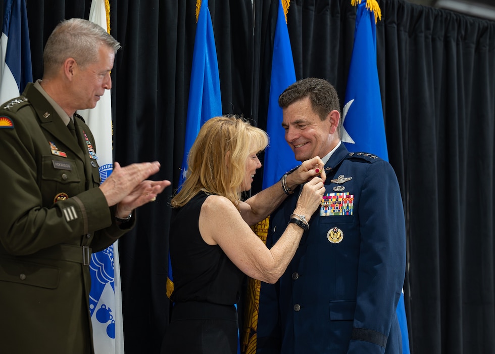 Dianne Loh, center, pins on a retirement lapel on U.S. Air Force Lt. Gen. Michael A. Loh.