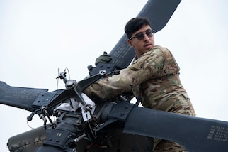 A photo of a Soldier inspecting a helicopter propeller.