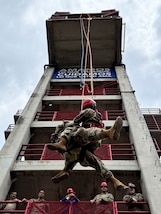 A photo of people repelling off a structure.