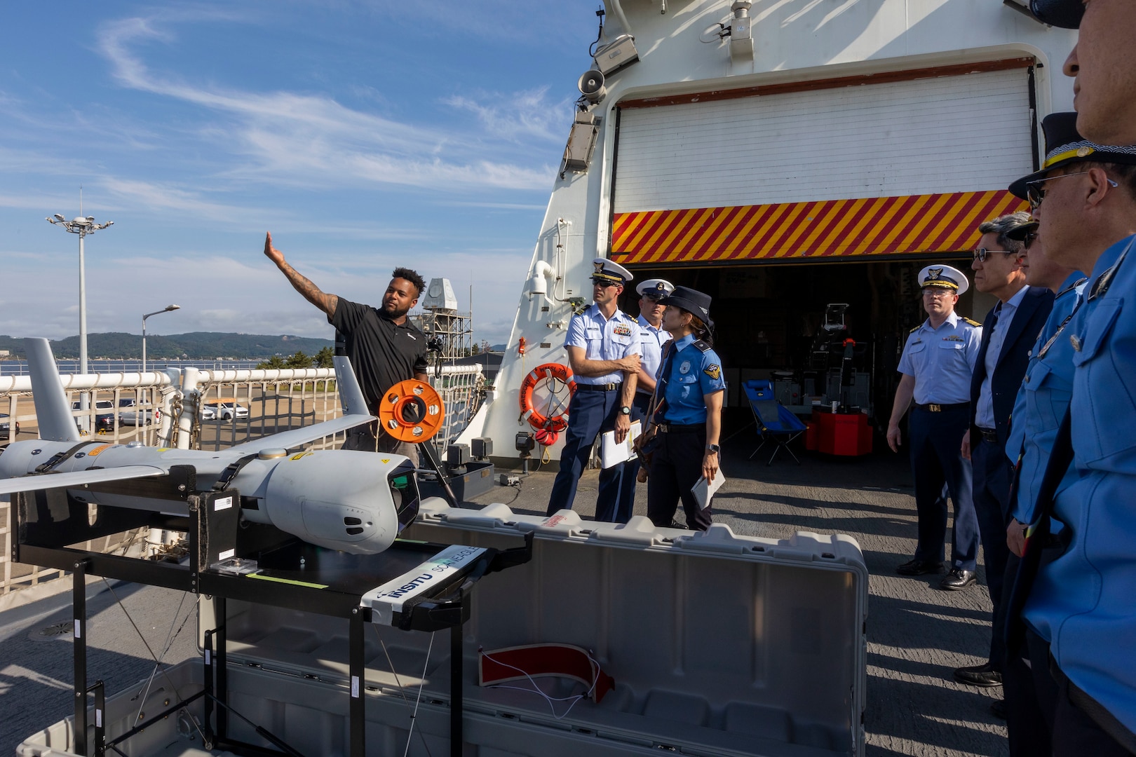 Christopher Lee, an operator of the ScanEagle small unmanned aerial system (UAS), working aboard the U.S. Coast Guard Cutter Waesche (WMSL-751), explains the role of UAS to leaders in the Korea Coast Guard, during a tour of the Waesche in Pohang, Republic of Korea, June 9, 2024. U.S. Coast Guardsmen welcomed leaders from the Korea Coast Guard and the mayor of Pohang aboard for a tour to highlight capabilities and best practices used by the U.S. Coast Guard. Waesche is assigned to Destroyer Squadron (DESRON) 15, the Navy’s largest DESRON and the U.S. 7th Fleet’s principal surface force. U.S. Coast Guard missions in the Indo-Pacific focus on issues directly supporting and advancing our regional partners’ efforts to protect fish stocks, ensure safety of life at sea, support environmental response, and provide disaster relief. (U.S. Marine Corps photo by Cpl. Elijah Murphy)