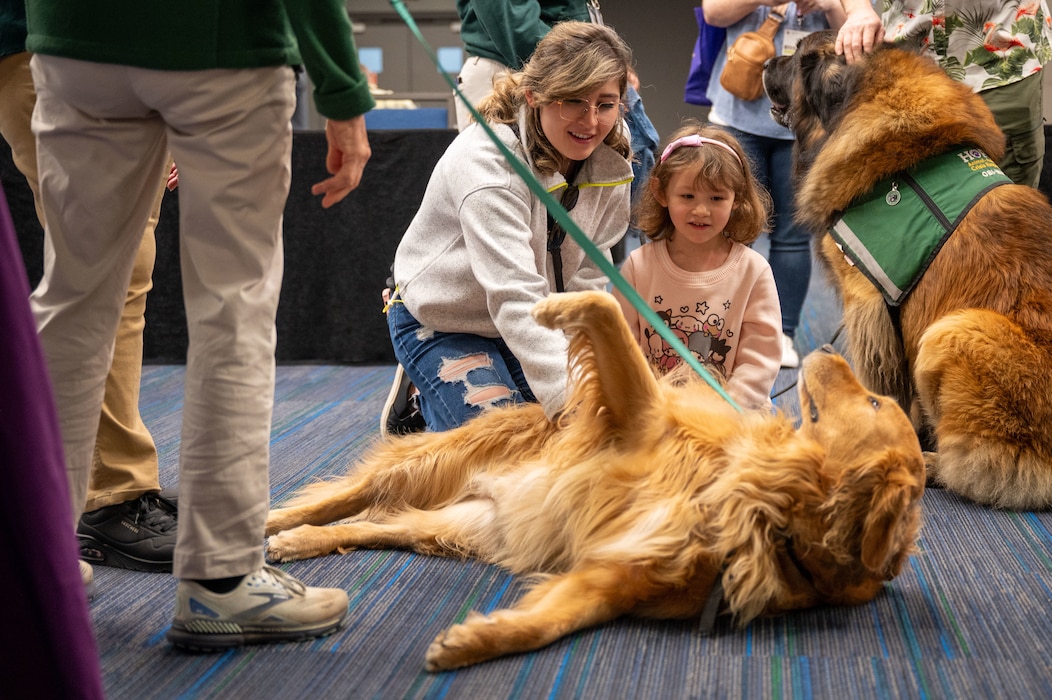 Photo of two people petting a golden retriever.