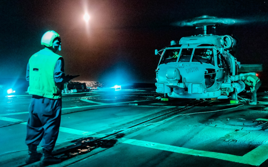 BM2 David Nieves signals to an MH-60R helicopter fromHSM-74 aboard USS Gravely (DDG 107) during flight quarters in the Mediterranean Sea.