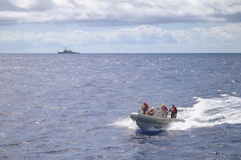 Sailors approach USS Curtis Wilbur (DDG 54) in a rigid-hull inflatable boat.