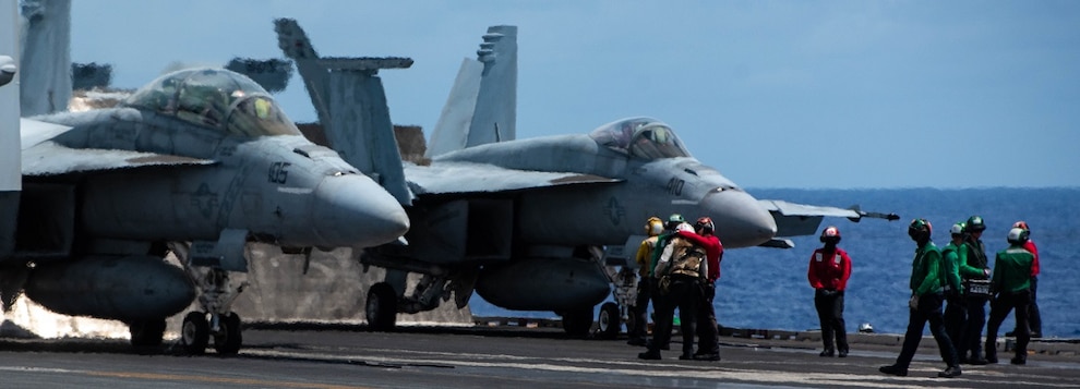 Sailors stand by as an F/A-18F Super Hornet, attached to the Diamondbacks of Strike Fighter Squadron (VFA) 102, and an F/A-18E Super Hornet, attached to the Dambusters of Strike Fighter Squadron (VFA) 195, prepare to launch.
