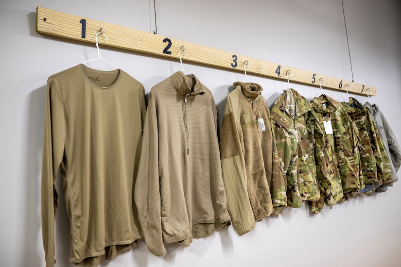 Seven pieces of long-sleeve clothing hang on a wall.