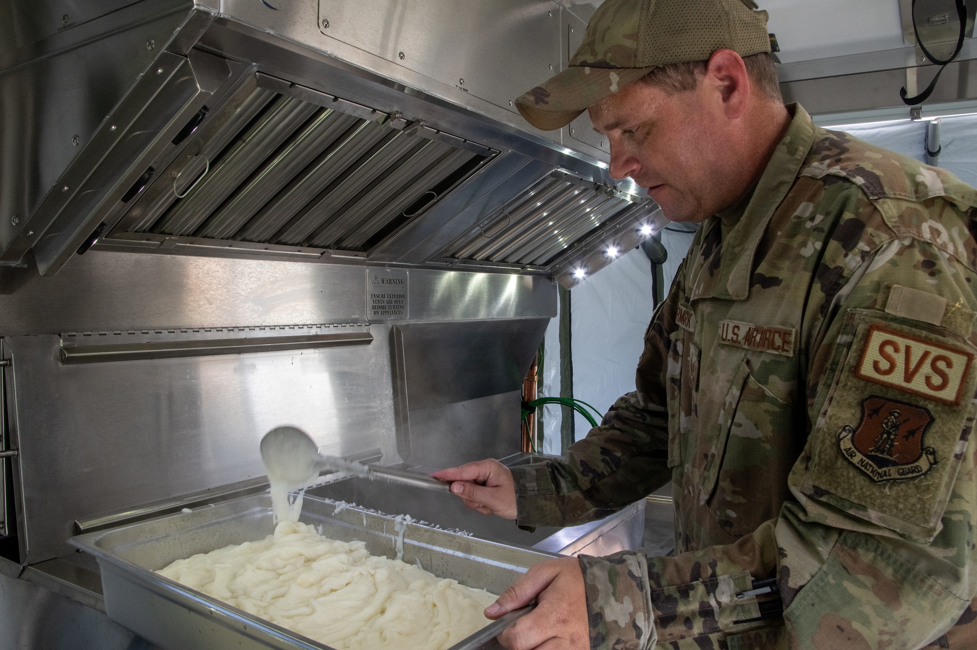 Air National Guard Airman prepares food inside the ESPEK kitchen wearing OCP patterned uniform.